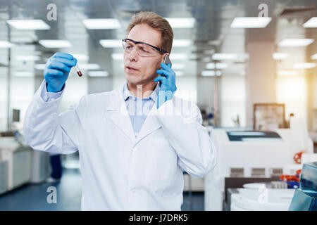 Ernsthaften Praktiker Telefon in der Nähe von linken Ohr halten Stockfoto