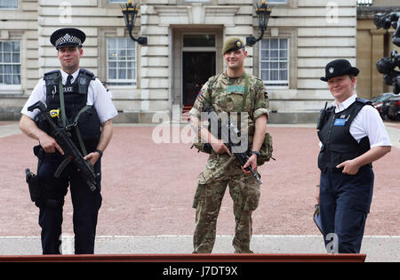 Ein Mitglied der Armee schließt sich Polizeibeamten vor dem Buckingham Palace, London, an, nachdem Scotland Yard angekündigt hatte, dass bewaffnete Truppen eingesetzt werden, um "Schlüsselorte" wie Buckingham Palace, Downing Street, den Palace of Westminster und Botschaften zu bewachen. Stockfoto