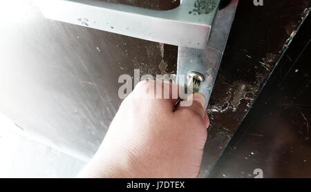 Nahaufnahme der Hand mit Schlüssel entriegeln der metallischen Tür. Stockfoto