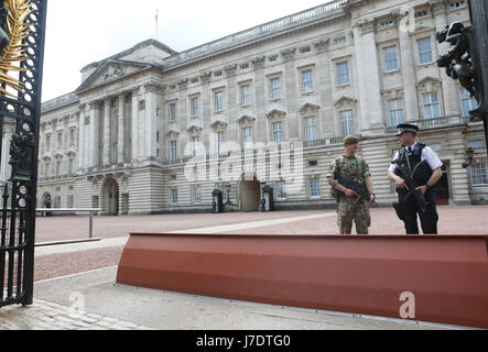 Ein Mitglied der Armee trifft sich vor dem Buckingham Palace, London, zu Polizeibeamten, nachdem Scotland Yard angekündigt hatte, dass bewaffnete Truppen eingesetzt werden, um wichtige Orte wie den Buckingham Palace, die Downing Street, den Palace of Westminster und Botschaften zu bewachen. Stockfoto