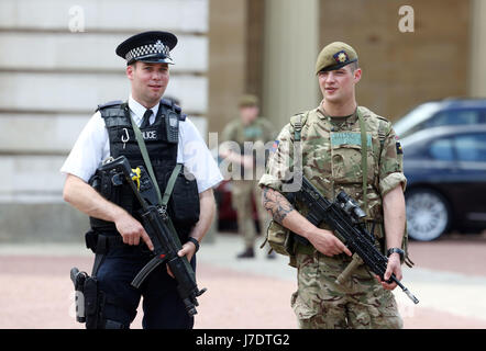 Ein Mitglied der Armee schließt sich Polizeibeamten vor dem Buckingham Palace, London, an, nachdem Scotland Yard angekündigt hatte, dass bewaffnete Truppen eingesetzt werden, um "Schlüsselorte" wie Buckingham Palace, Downing Street, den Palace of Westminster und Botschaften zu bewachen. Stockfoto