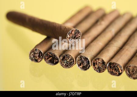 Nahaufnahme von paar Zigarren in einer Reihe auf gelbem Hintergrund Stockfoto