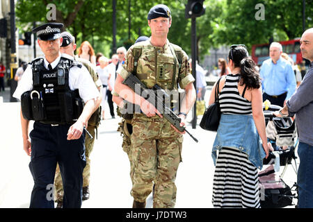 Ein Mitglied der Armee schließt sich Polizeibeamten in Whitehall, London, an, nachdem Scotland Yard angekündigt hatte, dass bewaffnete Truppen eingesetzt werden, um „wichtige Orte“ wie Buckingham Palace, Downing Street, den Palace of Westminster und Botschaften zu bewachen. Stockfoto