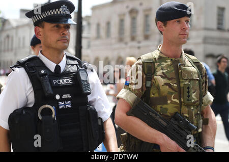 Ein Mitglied der Armee schließt sich Polizeibeamten in Whitehall, London, an, nachdem Scotland Yard angekündigt hatte, dass bewaffnete Truppen eingesetzt werden, um „wichtige Orte“ wie Buckingham Palace, Downing Street, den Palace of Westminster und Botschaften zu bewachen. Stockfoto