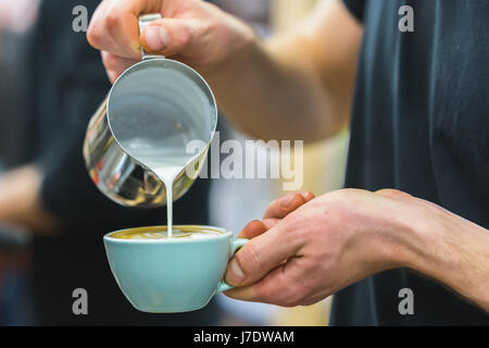 Barista in Vorbereitung richtigen Cappuccino strömenden aufgeschäumte Milch in Kaffee, Café Latte Kunst, Schnitterstellung zu machen. Professioneller Service, catering-Konzept Stockfoto