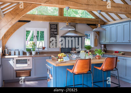 Helle Insel Einheit von Farrow & Ball in Eiche-gestaltete Küche mit Pendelleuchten in Toynbee blau lackiert Stockfoto