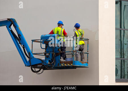 zwei Gipser arbeiten an der Wand eines Neubaus von einer Hubarbeitsbühne oder Hebebühne Stockfoto