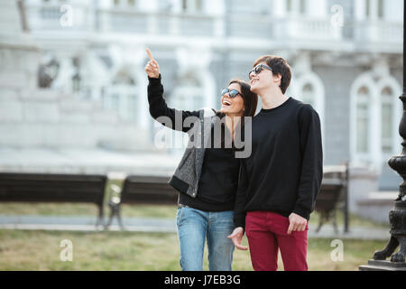 Bild der hübschen jungen Dame walking im Freien mit ihrem Bruder. Auf der Suche zur Seite und zeigen. Stockfoto