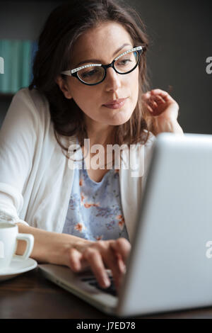Porträt von durchdachten Reife Geschäftsfrau Tippen auf Laptop sitzend am Tisch zu Hause Stockfoto