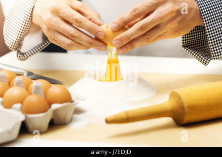 Bäckerei - Chef knacken Ei über Mehl Stockfoto