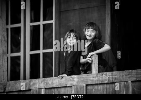 Schöne schwarz / weiss ehrliche natürliche Portraitbild von lächelnden Kinder aus dem indigenen Rennen Toraja Leute in Sulawesi stehend auf Balkon Stockfoto