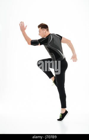 Voller Länge Porträt eines jungen konzentrierte Sportlers Kopfhörer springen isoliert auf weißem Hintergrund Stockfoto
