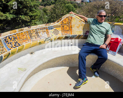 Ein Tourist sitzen auf einer Bank auf der Terrasse am Antoni Gaudis Park Güell, Barcelona, Spanien Stockfoto