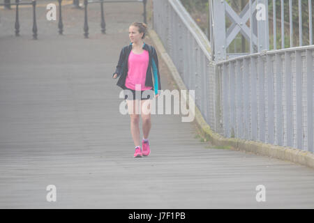 Ein Morgen Jogger immer einige Fitness in überqueren die Hängebrücke über den Fluss Dee in Chester an einem sehr neblig, nebligen Morgen im Sommer Stockfoto