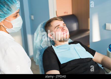 Porträt des Mannes. Lächeln Sie Gesicht. Zahnärztliche Versorgung Konzept. Zahnärztliche Untersuchung wird schöner Mann umgeben von Zahnarzt eingeräumt. Stockfoto