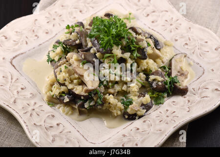 Blumenkohl-Risotto mit 3 Arten von Pilzen und Petersilie auf einem weißen Teller Stockfoto