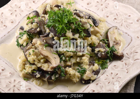 Blumenkohl-Risotto mit 3 Arten von Pilzen und Petersilie auf einem weißen Teller Stockfoto