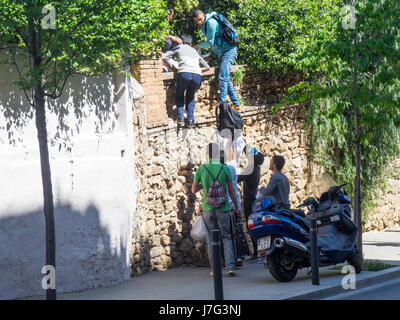 Verkäufer von gefälschten waren, die Flucht vor den Behörden durch die Skalierung einer Wand. Stockfoto