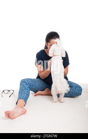 Hübsche Dame mit ihrem flauschigen Bichon kuscheln entspannen und spielen auf weißem Hintergrund Stockfoto