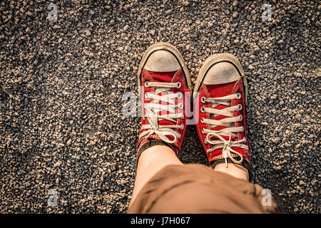 Füße im roten canvas Sneaker auf den Kiesweg Stockfoto