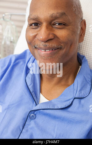 Glücklich senior African American Woman männlicher Patient erholt sich im Krankenhausbett mit blauen Schlafanzug tragen Stockfoto
