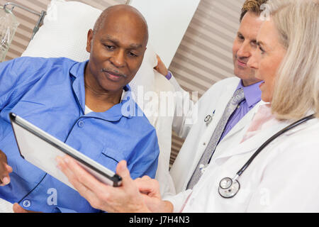 Senior-African-American Mann männlicher Patient erholt sich im Krankenhaus mit Mann und Frau Doktor Blick auf einem Tablet-computer Stockfoto