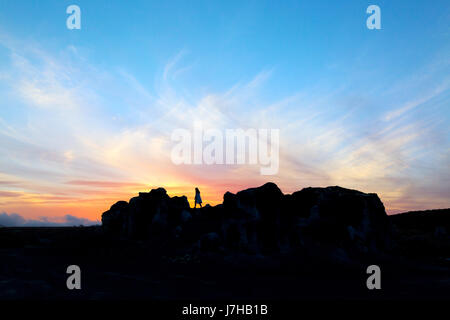 Lanzarote-Sonnenuntergang - eine Frau steht auf einem vulkanischen Felsen bei Sonnenuntergang, Lanzarote, Kanarische Inseln, Europa Stockfoto