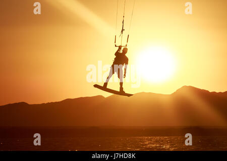 Kite Boarder Sportler mit Kite unter Sonnenuntergang Sonne, Freestyle Kiteboarding Reiter auf den Abend-Kite-Session, Sonnenuntergang im Meer, extreme watersports Stockfoto