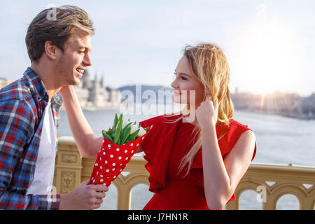 Glücklich Jüngling überraschend Frau mit Blumenstrauß im freien Stockfoto