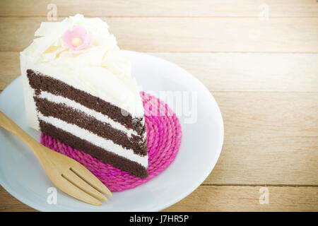 Stück Schokoladenkuchen mit Blume auf Holz Hintergrund Stockfoto