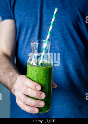 Grüner Smoothie. Mannhände halten Flasche mit frisch zubereiteten Detox grünen Smoothie. Nahaufnahme, selektiven Fokus Stockfoto