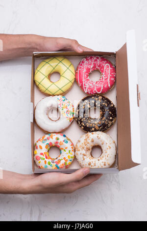 Hand, die bunte Runde Krapfen in der box Stockfoto