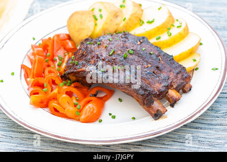 Gegrillte gegrilltes Schweinefleisch Baby Back Ribs serviert mit Kartoffeln und Gurken Stockfoto