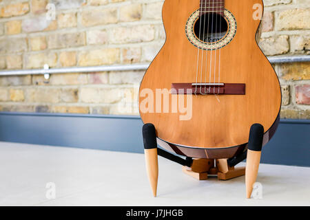 6-saitigen Gitarre auf einem Ständer, gegen innere Mauer mit industrielle elektrische Leitung Stockfoto