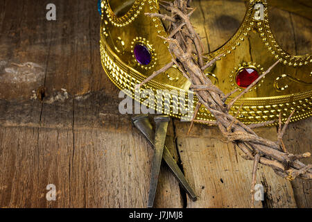 Goldkrone mit Dornenkrone auf rustikalen Holz mit rostigen Nägeln Stockfoto