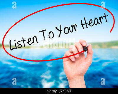 Hand des Mannes hören To Your Heart mit schwarzem Filzstift auf Bildschirm zu schreiben. Isoliert auf Natur. Wirtschaft, Technologie, Internet-Konzept. Stock Foto Stockfoto