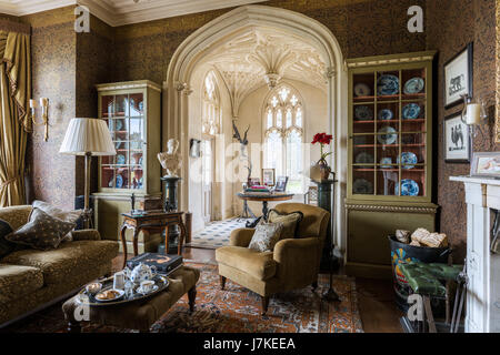 Mustertapeten von Zuber in Bibliothek mit antiken Perserteppich und gotischen Fenstern. Die Sofas und Sessel sind aus Beaumont & Flectcher Stockfoto