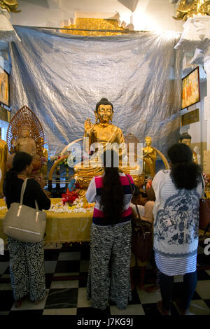 Kandy Sri Lanka Tempel der heiligen Zahn Frauen vor Golden Buddha mit Usnisa und in Vitarka-Mudra-Geste der Diskussion und Übertragung der Lehren des Buddha Stockfoto