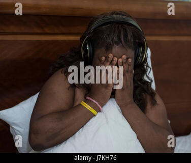 can not sleep, plus sized model with headphones, head in hands Stockfoto