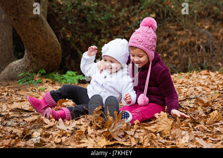 Niedliche Kinder freuen sich über die Blätter fallen, In der Natur Stockfoto