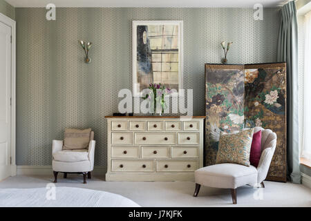 Chaiselongue im Schlafzimmer mit Farrow & Ball Lattice Wallpaper. Der Bildschirm ist Chinesisch und die Art-deco-Stil-Wandleuchten Ourced Retrouvius waren Stockfoto