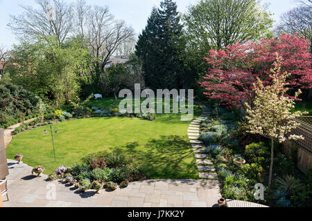 S Garten mit gepflasterten Gehweg, Rasen und verschiedene Anpflanzungen. Stockfoto