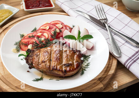 Schweineschnitzel mit Gemüse, Dill und Knoblauch Greens, dekoriert mit Minze mit Senf und Ajika Stockfoto