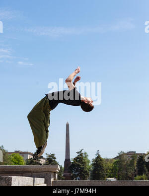 Junger Mann tut einen Back Flip im Hintergrund Obelisk. Parkour im urbanen Raum. Sport in der Stadt. Sportliche Aktivität. Stockfoto