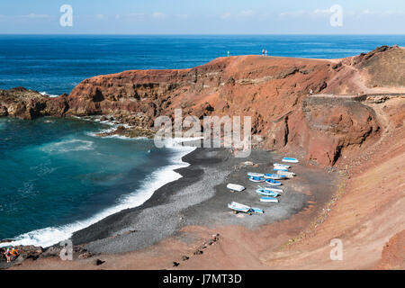 Strand und Küste mit einigen Booten in El Golfo in Lanzarote, Spanien. Stockfoto