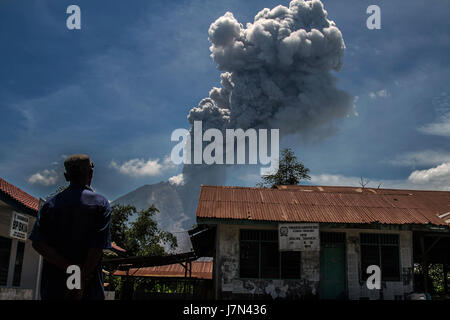 Karo, Nord-Sumatra, Indonesien. 25. Mai 2017. Ein Bewohner beobachtete, wie der Vulkan Sinabung spuckt rollenden dicken vulkanischen Asche in die Luft, von Tiga Pancur Dorf am 25. Mai 2017, Provinz Nord-Sumatra, Indonesien gesehen. Die Aktivität des Mount Sinabung mit dem Status von Awas (Stufe IV) erhöht sich die vulkanischen Erdbeben haben weiterhin mit Ausschlag schaffen eine Aschewolke von etwa 4.000 Metern Höhe auftreten. Mount Sinabung gehört zu den aktivsten Vulkan in Indonesien. Bildnachweis: Ivan Damanik/ZUMA Draht/Alamy Live-Nachrichten Stockfoto