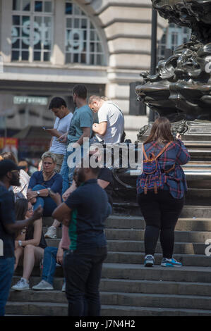 London, UK. 25. Mai 2017. Pendler und Touristen genießen heißen Sonnenschein und hohen Temperaturen heute Morgen. Touristen im kühlen Schatten im Eros am Piccadilly Circus. Bildnachweis: Malcolm Park Leitartikel/Alamy Live-Nachrichten. Stockfoto