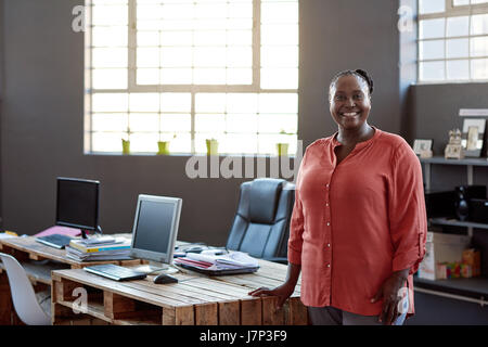 Lächelnde afrikanische Unternehmer stehen an ihrem Schreibtisch im Büro Stockfoto
