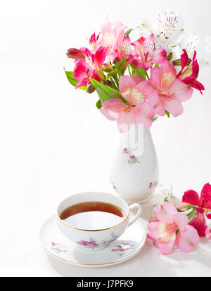 Retro-Stillleben mit Tasse Tee und Blumen (Alstroemeria) Stockfoto