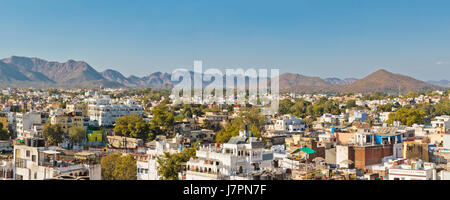 Panoramablick von Gebäuden, umgeben von grünen Bäumen gegen blauen Himmel in Udaipur Stockfoto